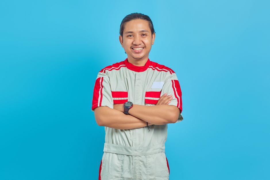 Friendly HVAC technician standing next to a residential unit